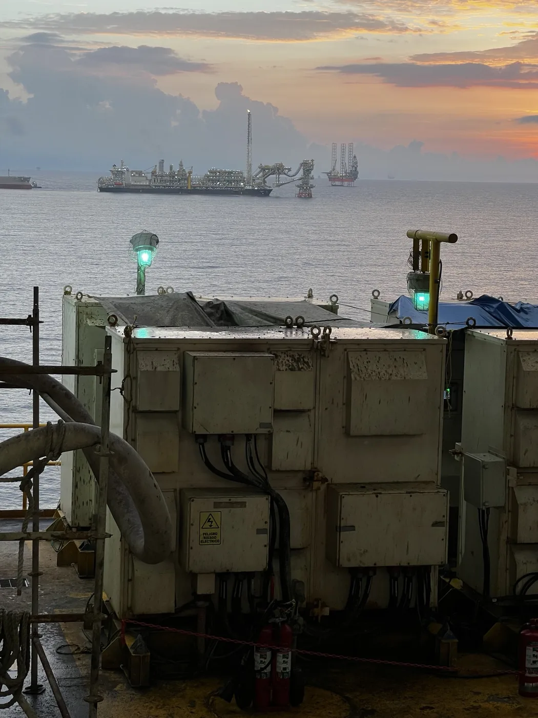 Panorámica offshore al atardecer con embarcación y plataformas en el horizonte